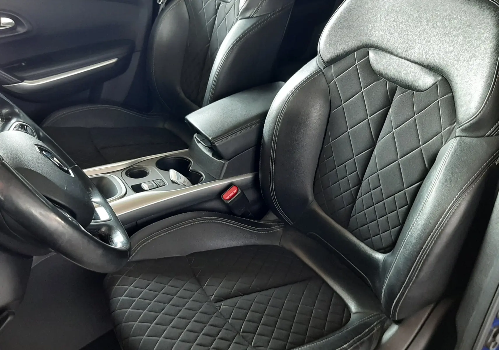 Vue intérieure côté conducteur du Renault Kadjar 2020 bleu iron, sièges noirs en cuir et tissu matelassé avec console centrale visible.