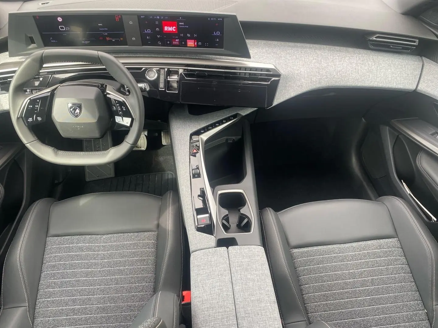 Vue intérieure avant du Peugeot 3008 2025, volant cuir multifonction et console centrale avec accoudoir gris clair.