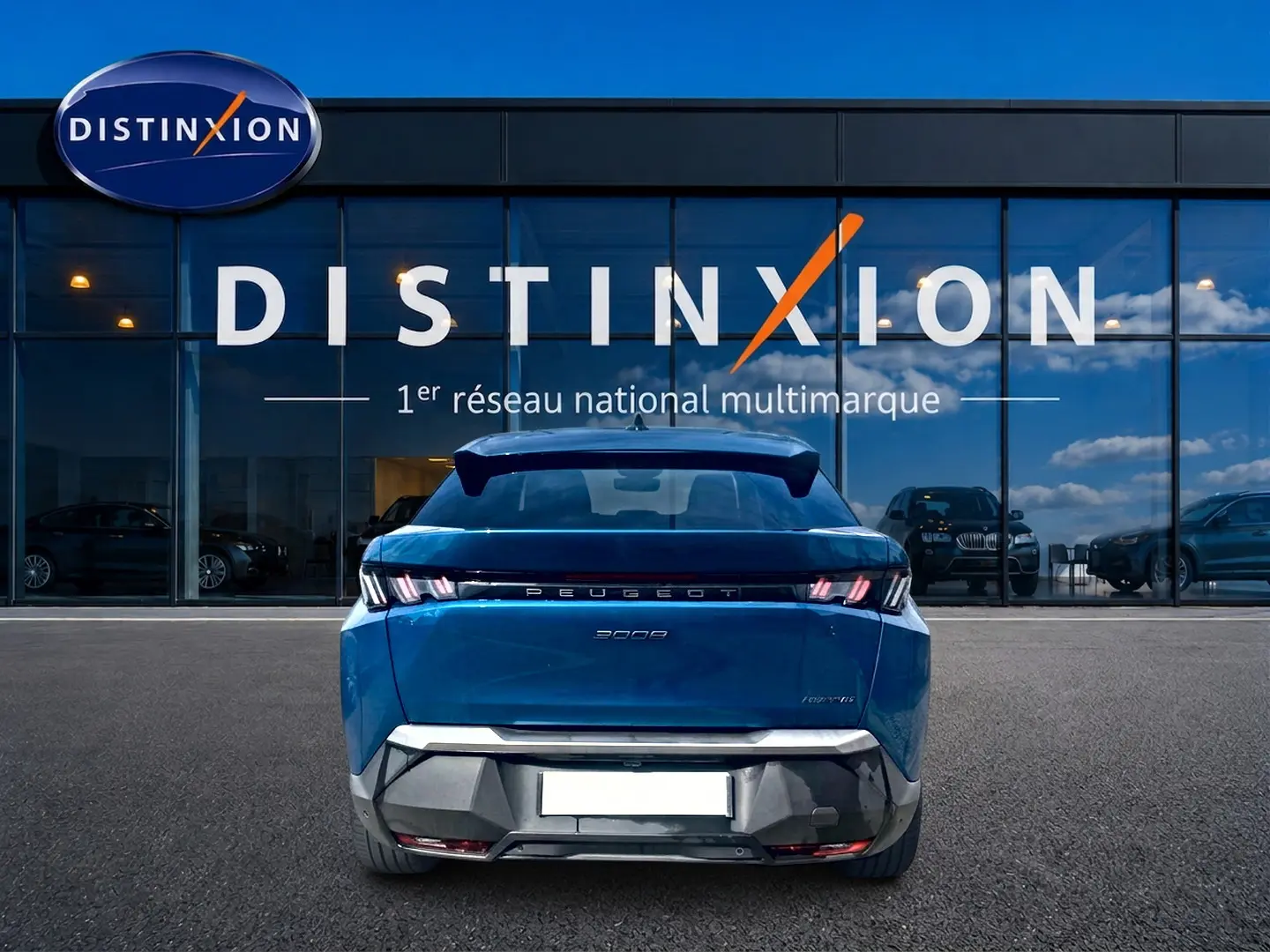 Vue arrière du Peugeot 3008 hybride bleu obsession 2025, avec feux LED et becquet arrière visible devant un showroom Distinxion.