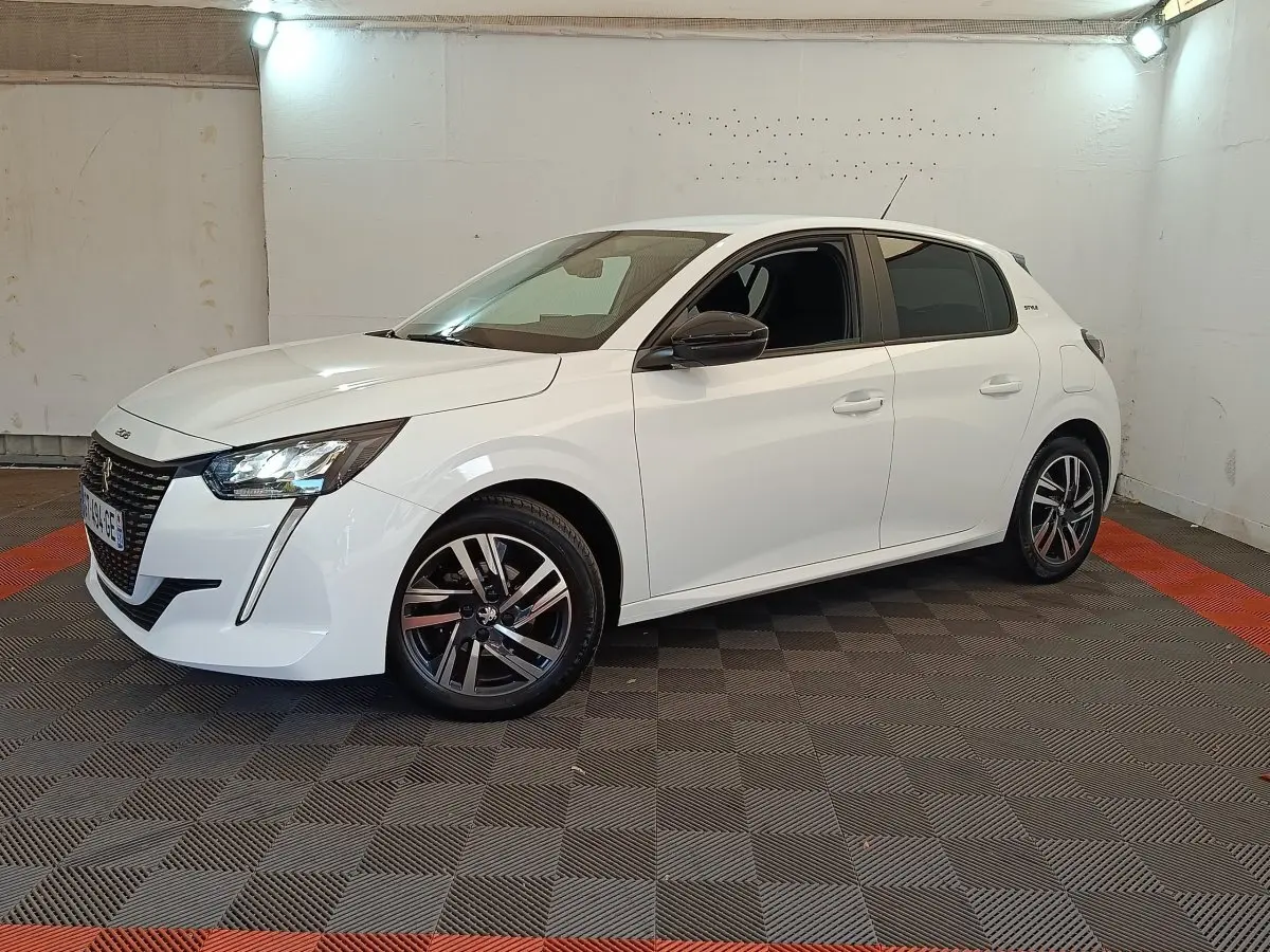 Peugeot 208 PureTech 75 S&S Style blanc vue 3/4 avant droit dans un espace intérieur éclairé.