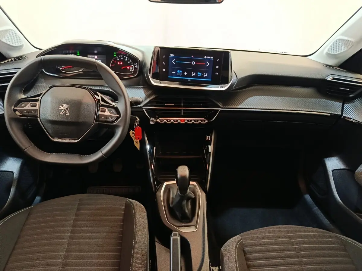 Vue intérieure avant du tableau de bord de la Peugeot 208 blanche, volant cuir multifonctions et écran tactile central.