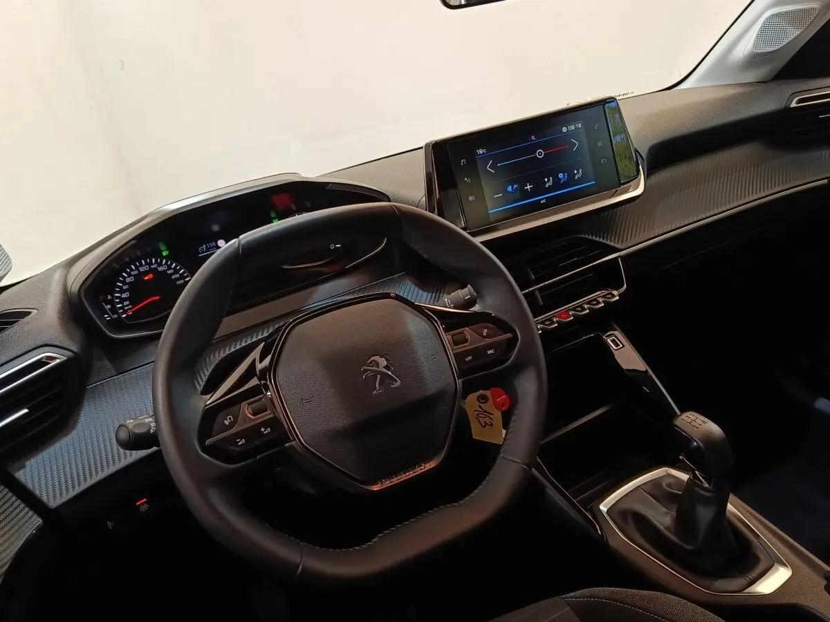 Vue intérieure centrée sur le volant cuir multifonctions et la console centrale avec écran tactile de la Peugeot 208 2023.