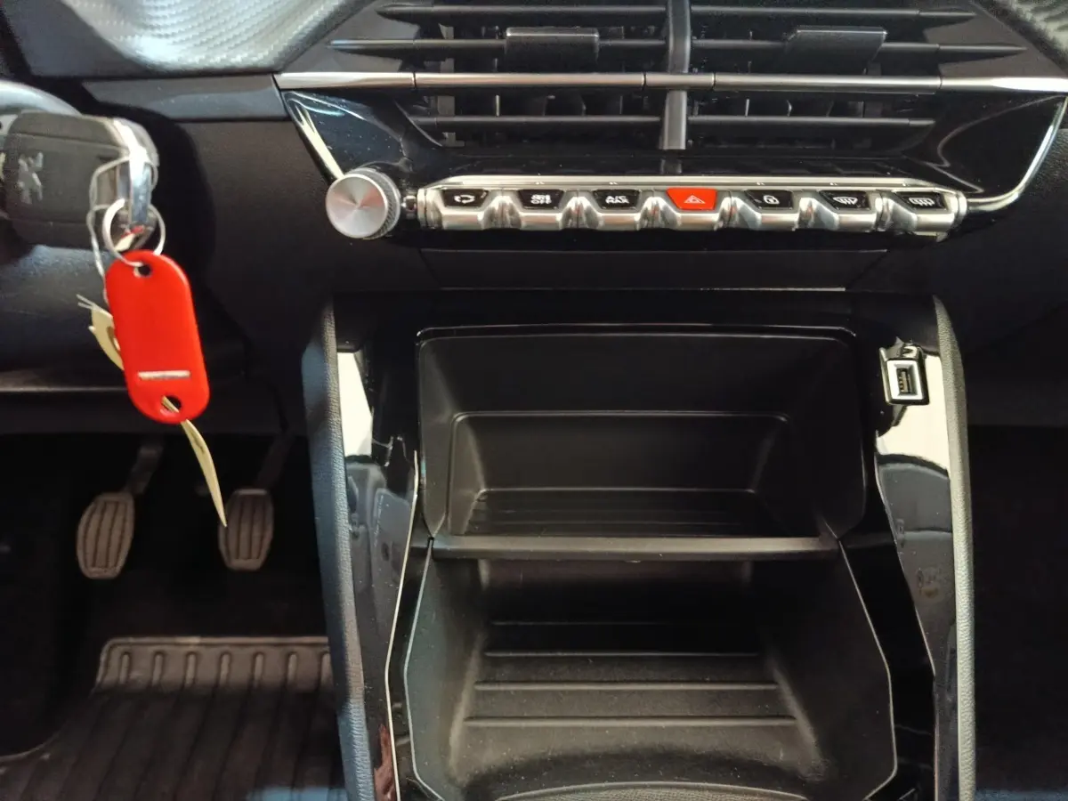Vue rapprochée de la console centrale noire d’une Peugeot 208 PureTech 75 S&S Style avec clés et pédales visibles.