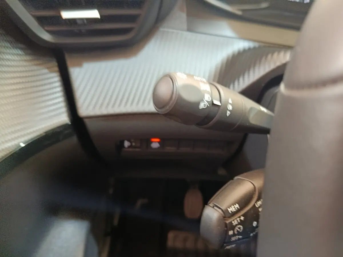 Détail intérieur du combiné de commandes au volant cuir d’une Peugeot 208 blanche, version PureTech 75 S&S Style 2023.