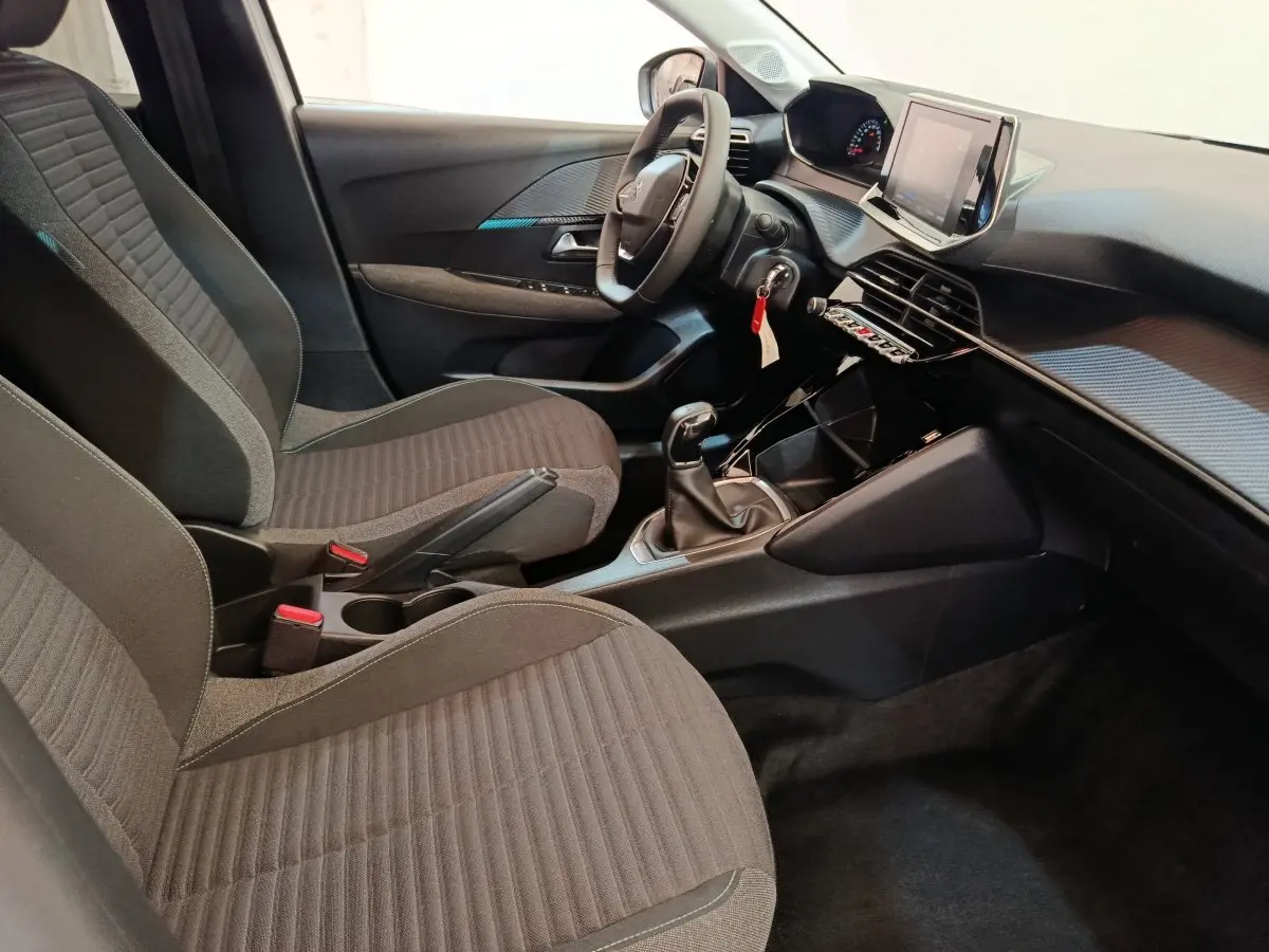 Intérieur de la Peugeot 208 PureTech 75 S&S Style 2023, vue côté conducteur, sièges tissu gris et tableau de bord moderne.