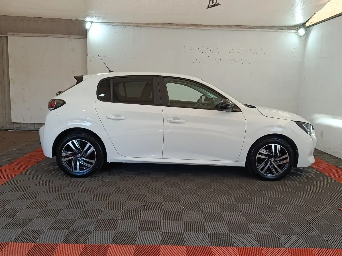 Profil droit d'une Peugeot 208 blanche 2023, avec jantes alliage noires et rétroviseurs ton caisse.