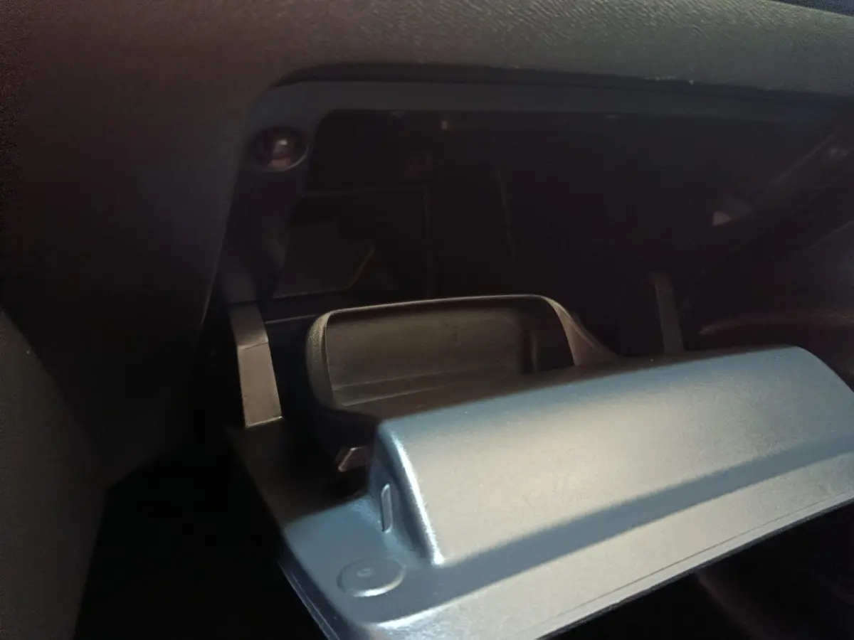 Gros plan sur le compartiment à gants ouvert de la Peugeot 208 PureTech 75 S&S Style, intérieur noir.