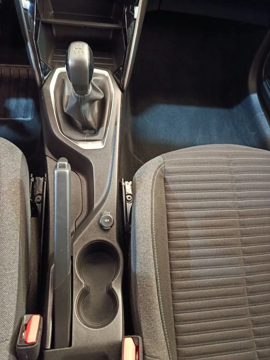 Vue plongeante sur la console centrale intérieure de la Peugeot 208 blanche, avec levier de vitesse manuel et siège tissu gris.