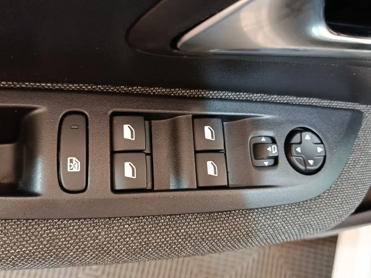 Détail des commandes des vitres et réglages des rétroviseurs sur la porte côté conducteur d’une Peugeot 208 blanche.