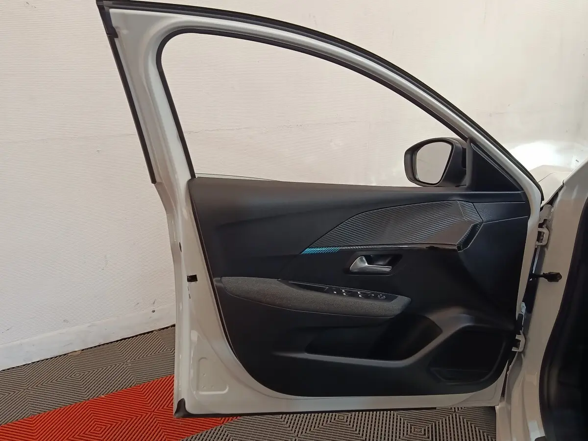 Vue intérieure de la porte avant gauche blanche d'une Peugeot 208 2023, avec garniture noire et détails texturés.