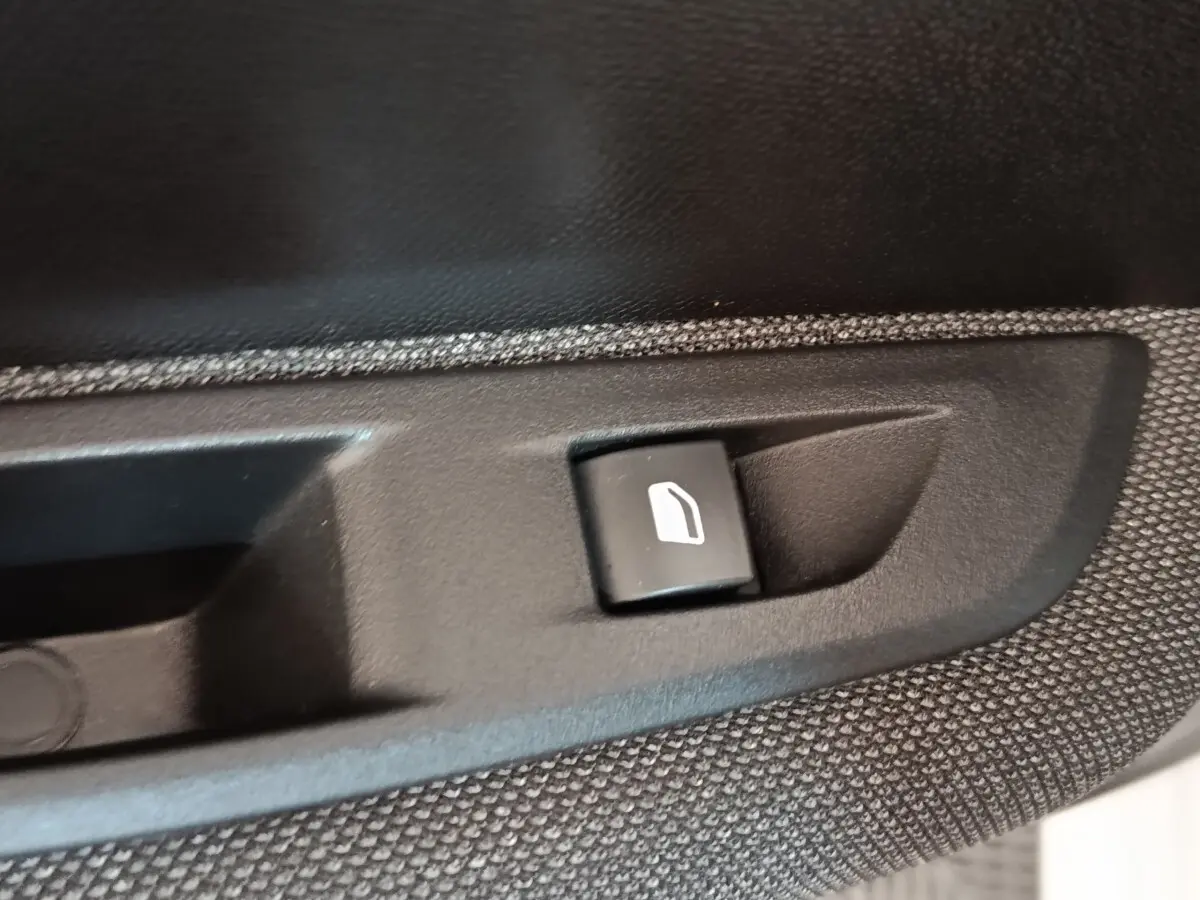 Gros plan sur le bouton de commande de lève-vitre électrique côté conducteur de la Peugeot 208 blanche 2023.