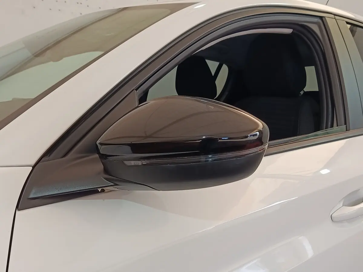 Rétroviseur noir brillant côté conducteur d'une Peugeot 208 blanche PureTech 75 S&S Style 2023, vue latérale rapprochée.
