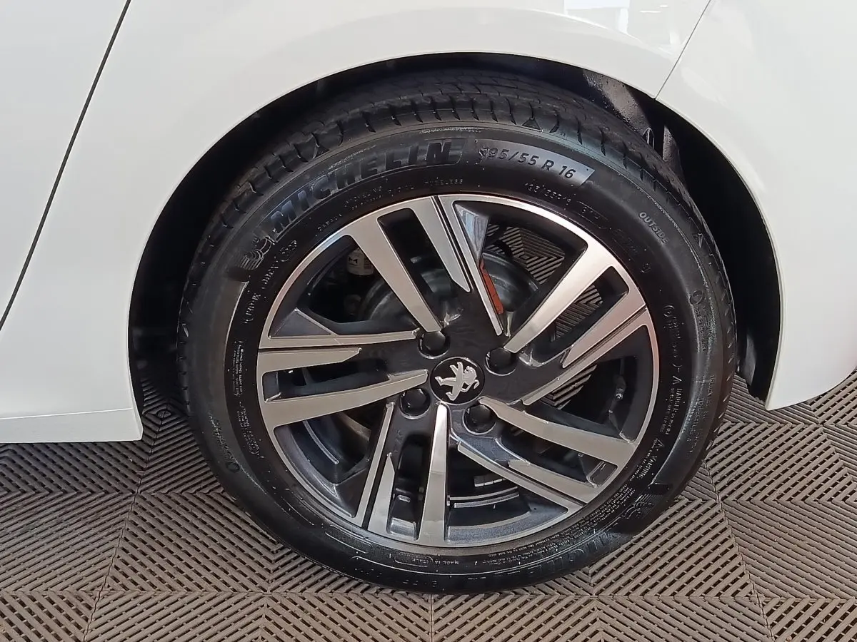 Gros plan sur la roue arrière droite blanche d'une Peugeot 208 PureTech 75 S&S Style avec jante alliage noire et argent.