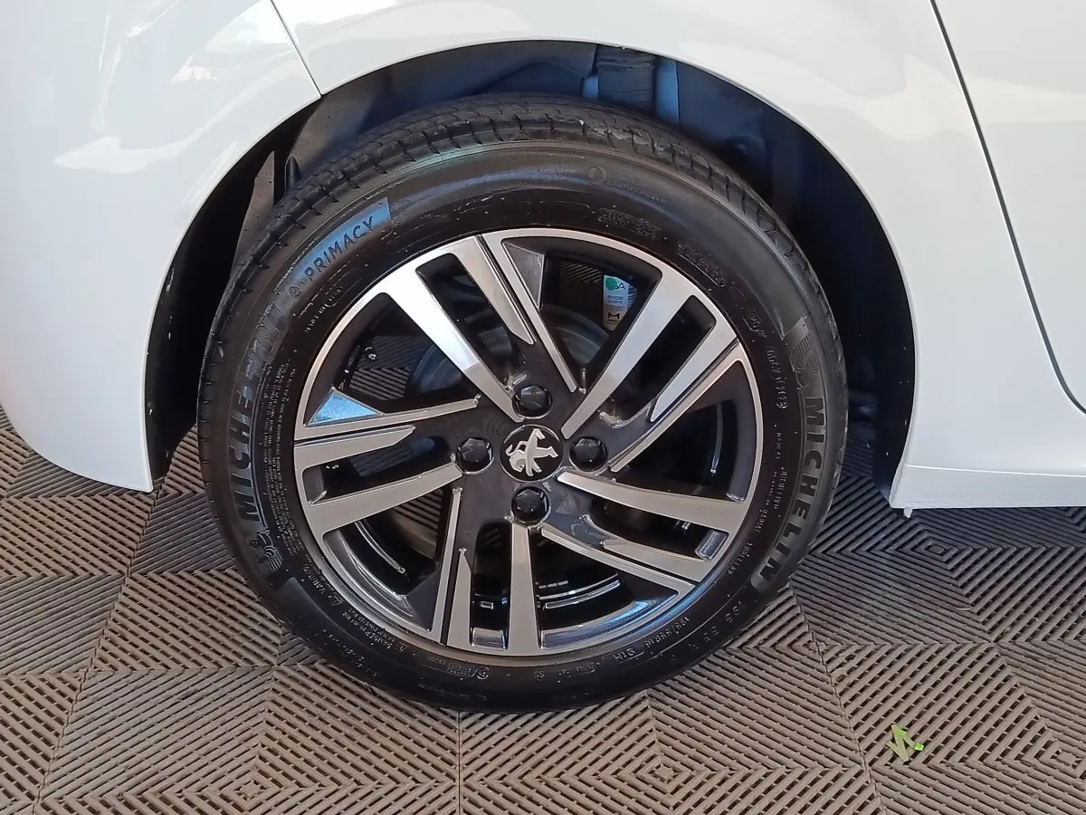 Gros plan sur la roue avant droite d'une Peugeot 208 blanche, jante alliage bicolore et pneu Michelin.