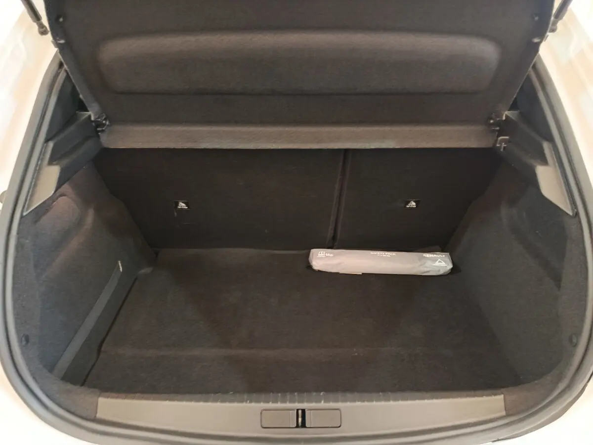 Coffre ouvert d'une Peugeot 208 blanche, vue de l'arrière, montrant un espace de chargement vide avec un kit de sécurité.