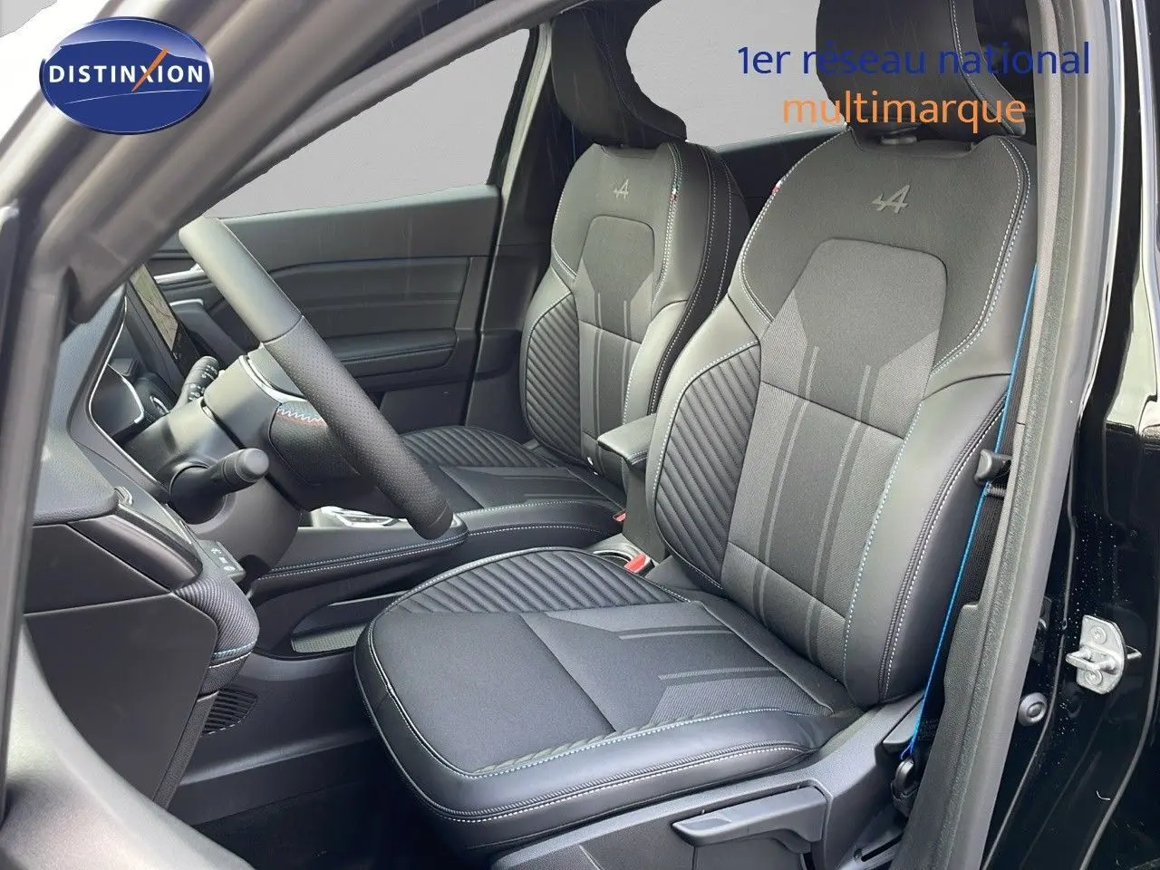 Intérieur du Renault Captur E-Tech hybride 2025, sièges avant noirs avec surpiqûres bleues et logo Alpine brodé.
