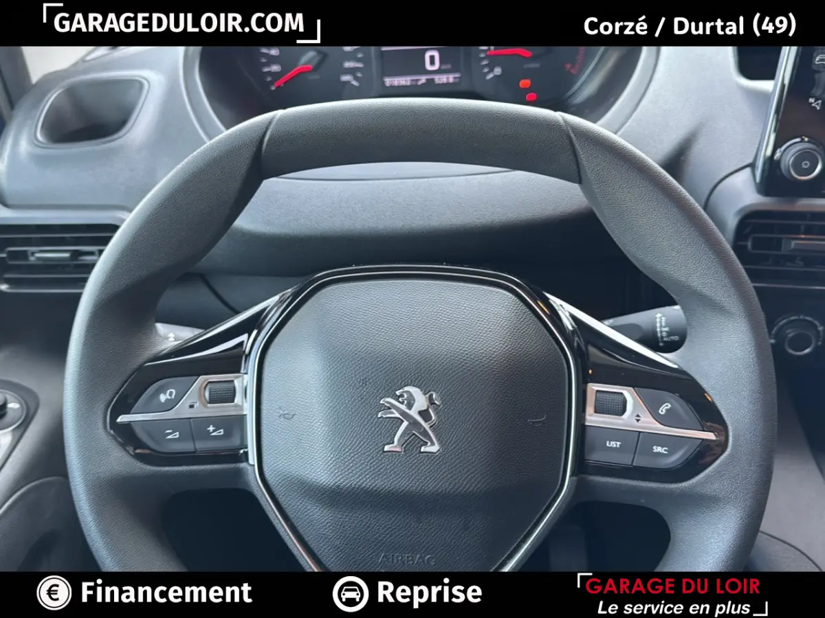 Vue rapprochée du volant noir du Peugeot Rifter 2024 avec commandes intégrées et tableau de bord numérique en arrière-plan.