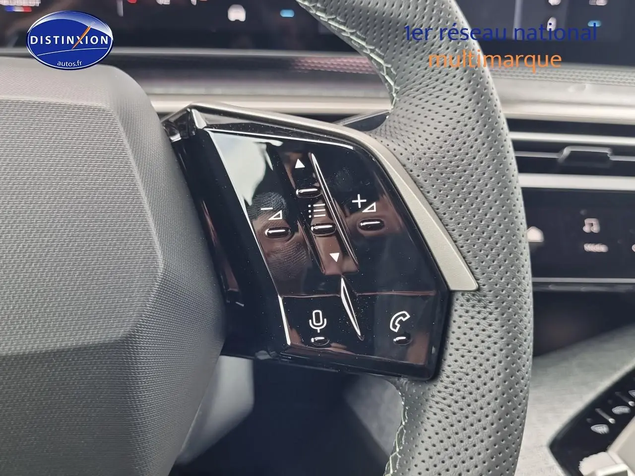 Gros plan sur les commandes vocales et audio du volant cuir perforé d'un Peugeot 3008 blanc, version hybride 2025.