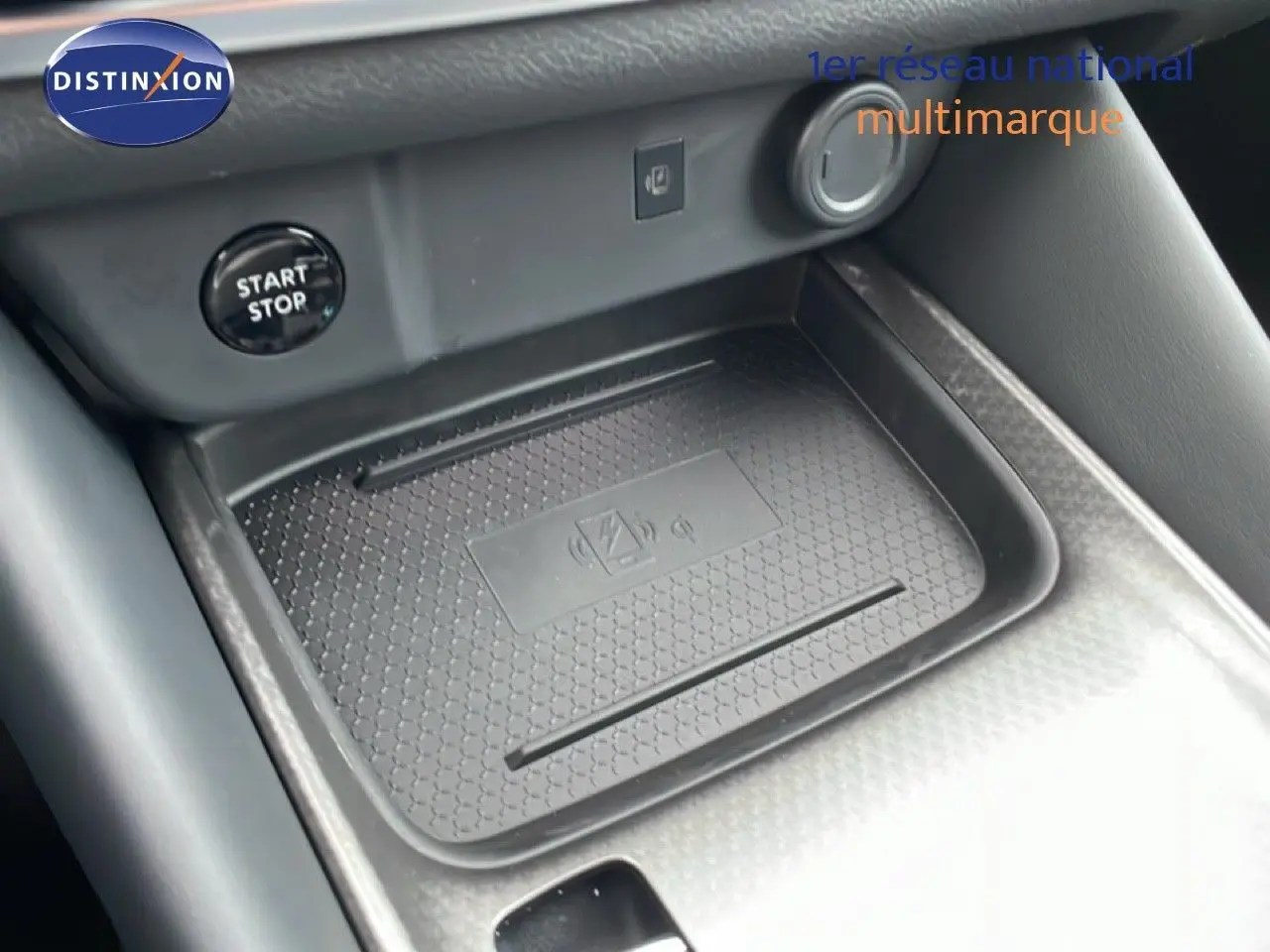 Gros plan sur le chargeur sans fil et bouton start/stop dans l'habitacle du Nissan Qashqai blanc nacré 2025.