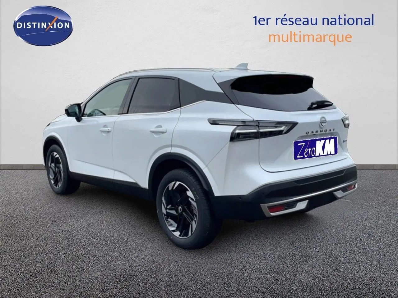 Vue 3/4 arrière droite d'un Nissan Qashqai blanc nacré métal 2025 avec jantes noires et toit noir contrasté.