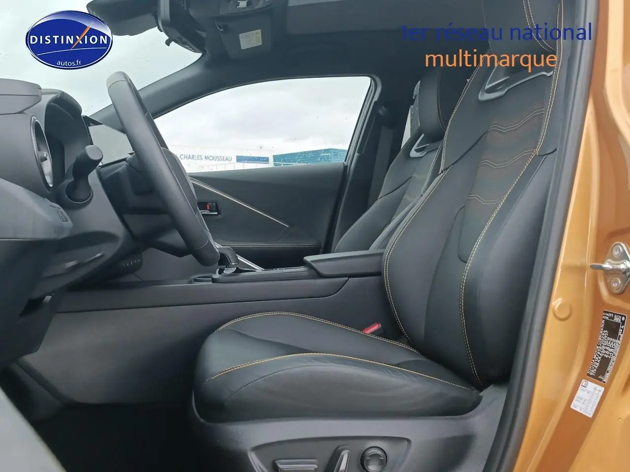 Vue intérieure côté conducteur du Toyota C-HR hybride 2025 or/noir, avec sièges sport noirs et surpiqûres jaunes.