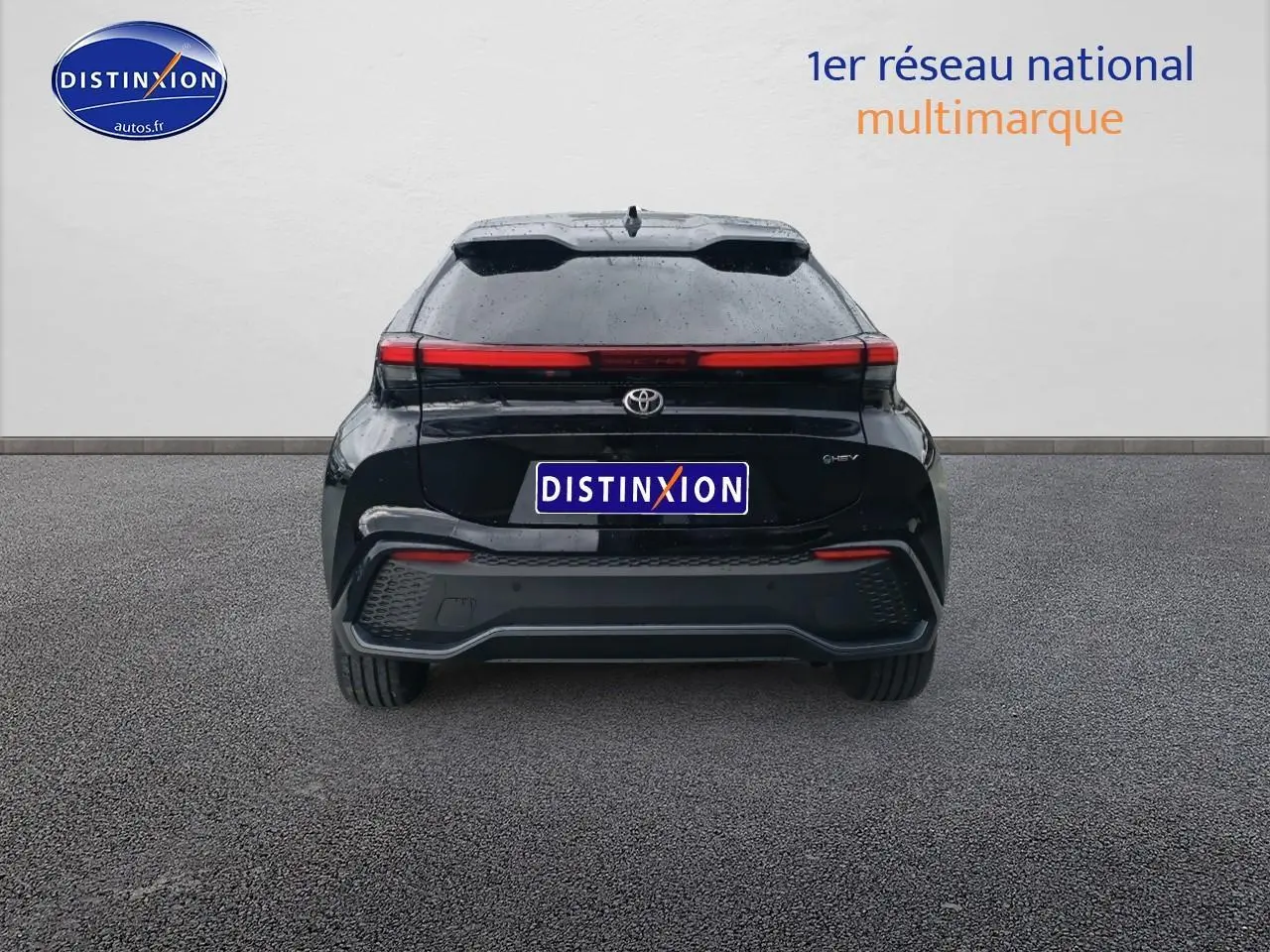 Vue arrière d'un Toyota C-HR hybride 2025 noir avec feux arrière LED en bandeau et toit panoramique visible.