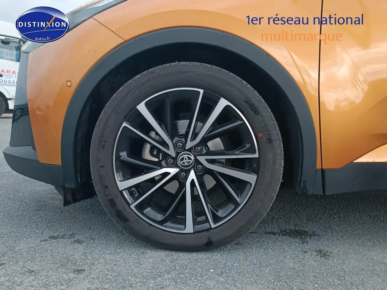 Gros plan sur la roue avant gauche du Toyota C-HR or et noir, avec jante alu bicolore et logo Toyota central.