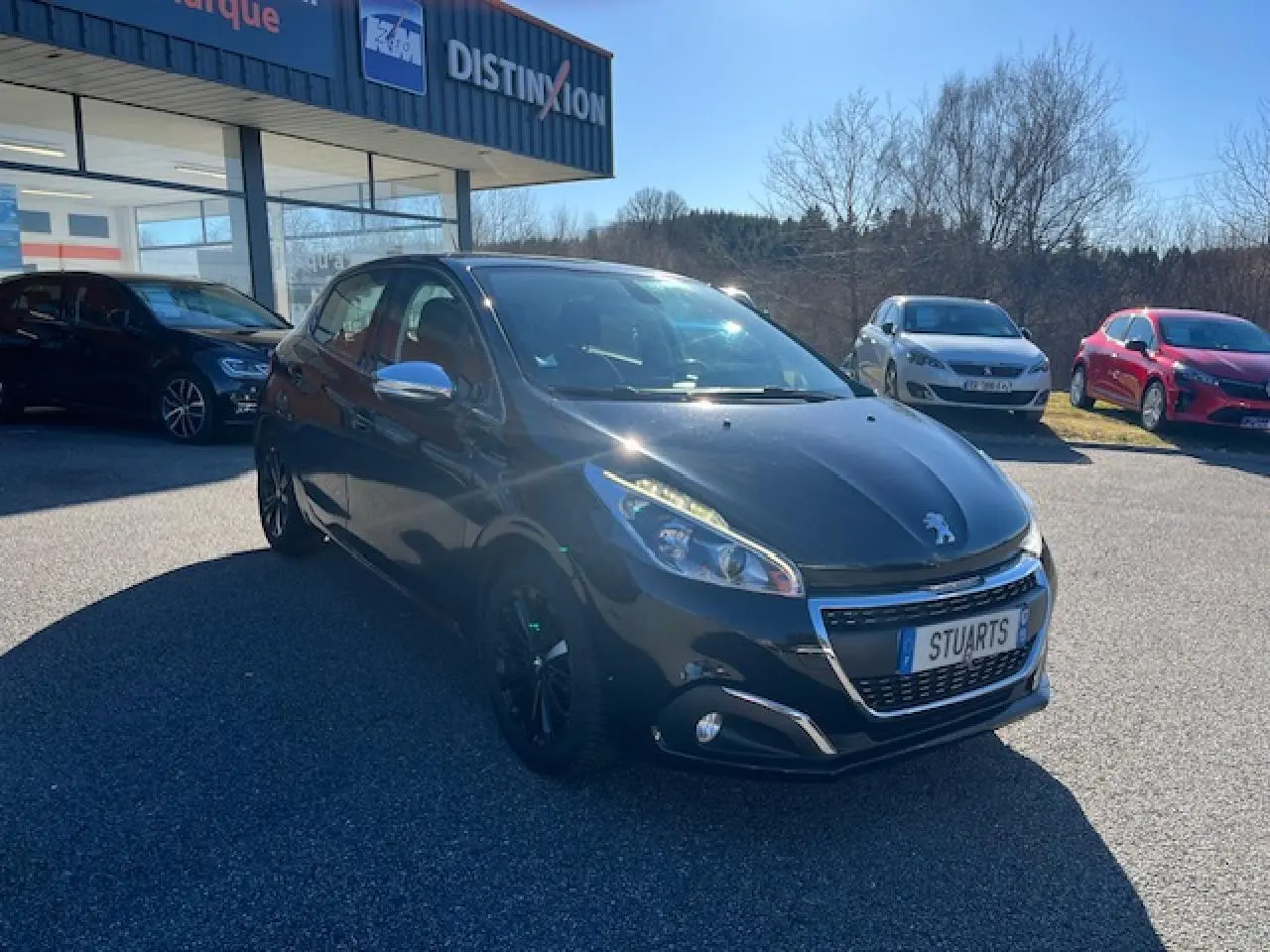 Peugeot 208 noire vue en 3/4 avant droit, avec jantes noires et calandre chromée brillante.