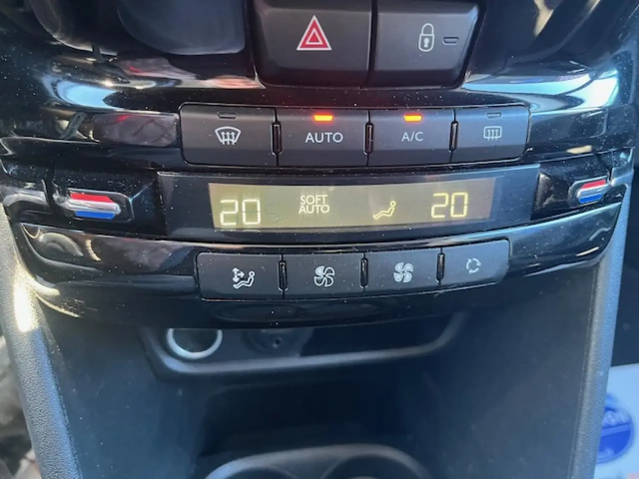 Gros plan sur la console centrale de la Peugeot 208 noire, affichant la climatisation automatique réglée à 20°C.