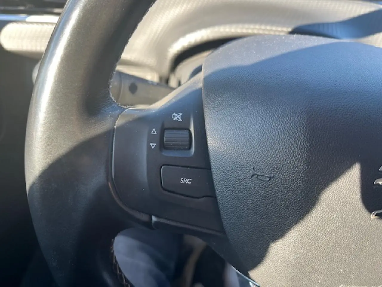 Gros plan sur le volant noir multifonction de la Peugeot 208 2017, avec commandes audio visibles à gauche.