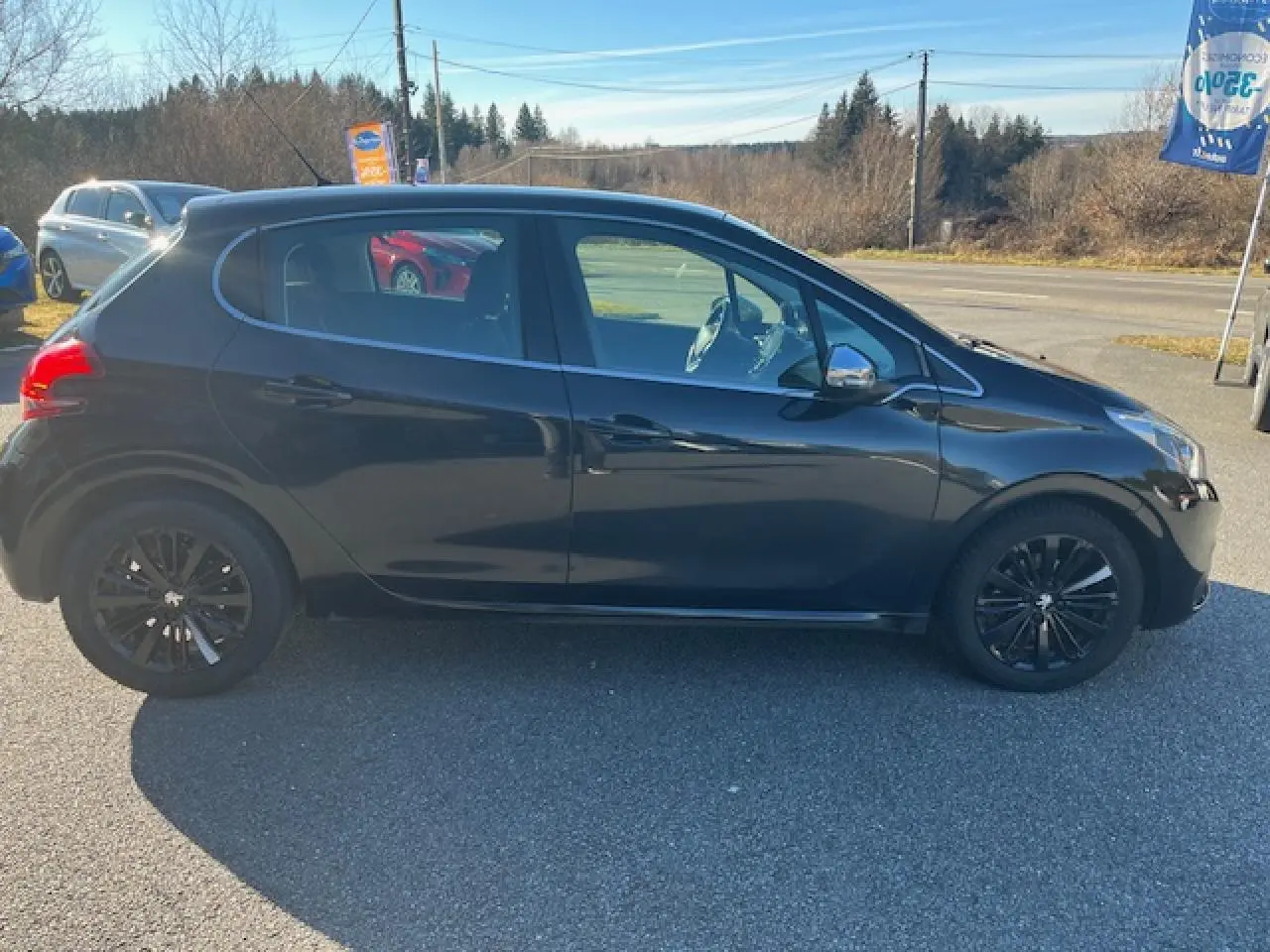 Profil côté gauche d'une Peugeot 208 noire de 2017 avec jantes noires et rétroviseurs chromés, stationnée en extérieur.