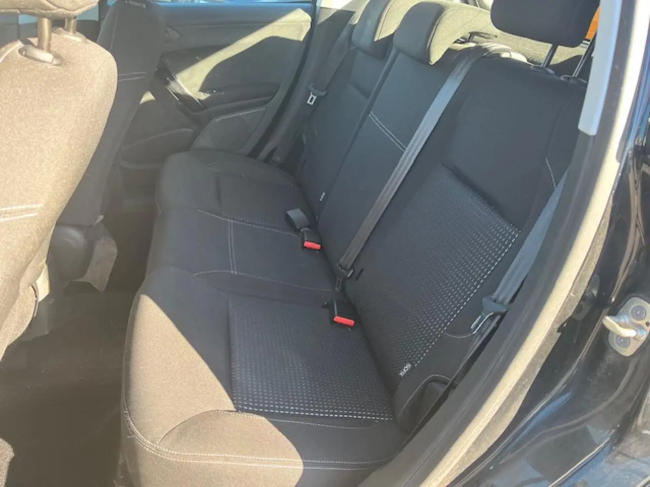Vue intérieure côté droit montrant la banquette arrière noire de la Peugeot 208 2017 avec ceinture de sécurité et porte ouverte.