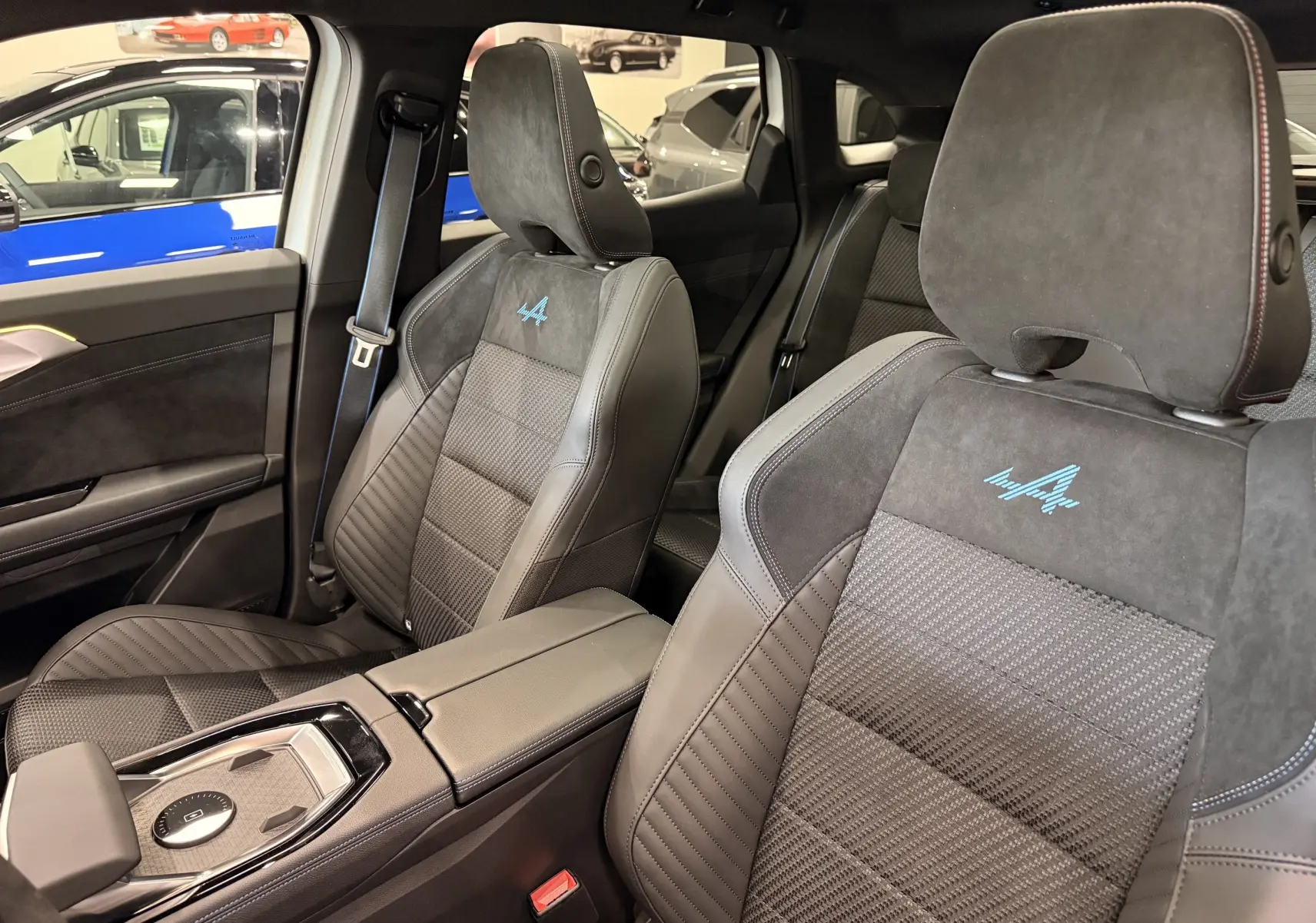 Vue intérieure des sièges avant du Renault Austral Esprit Alpine, cuir noir avec logo Alpine bleu brodé.