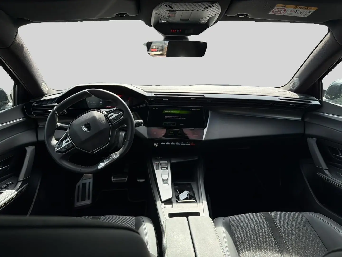 Vue intérieure avant de la Peugeot 308 noire 2025, avec tableau de bord numérique et volant multifonction compact.