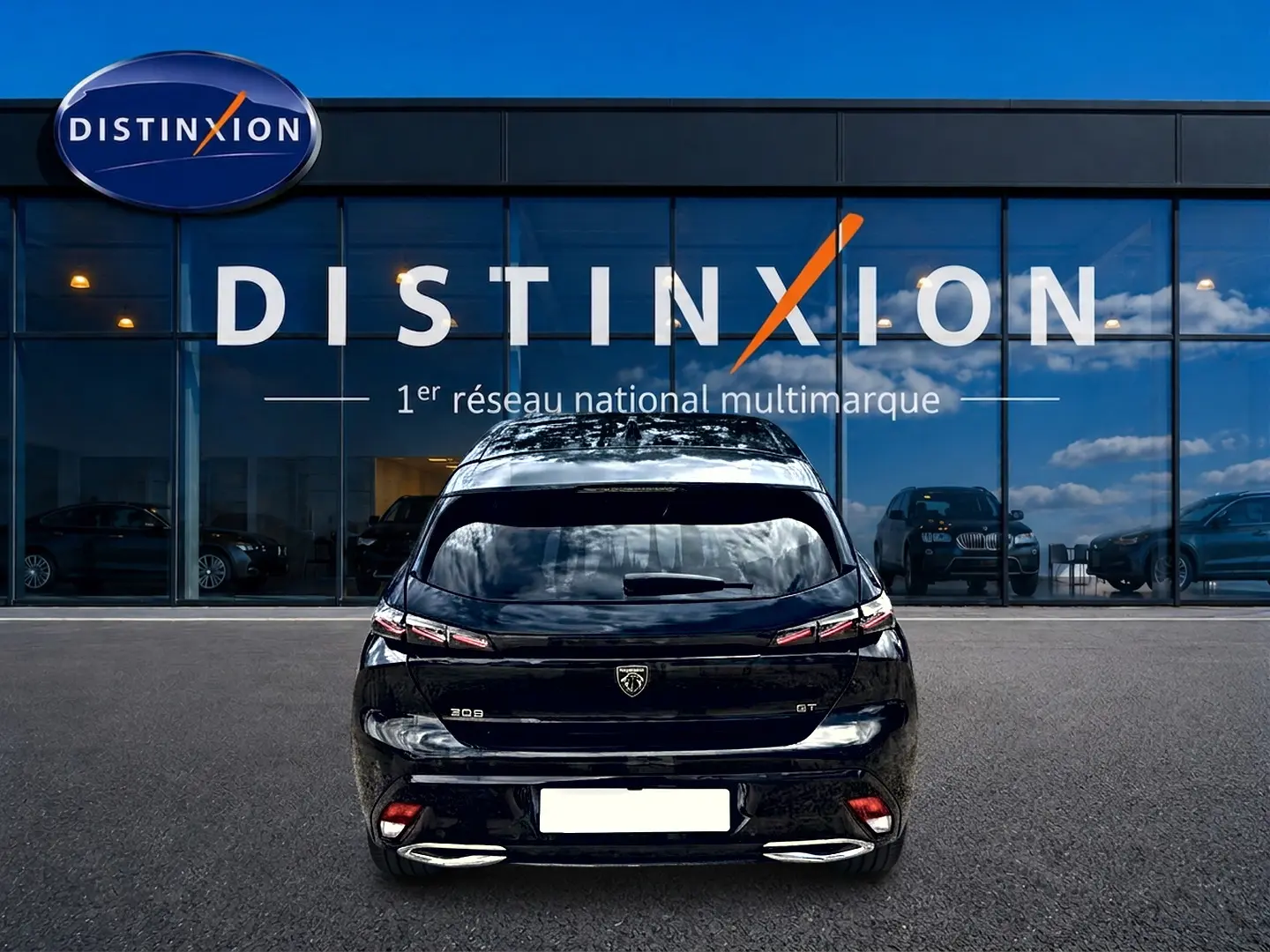 Vue arrière d'une Peugeot 308 noire 2025 GT avec feux LED et double sortie d'échappement chromée, devant une vitrine Distinxion.
