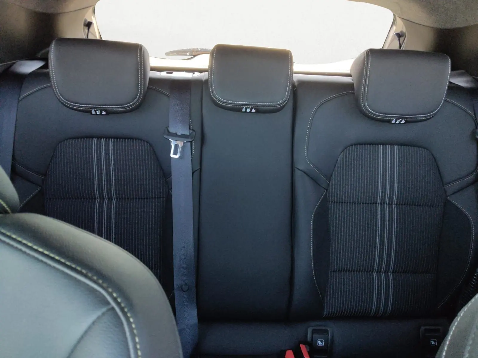 Vue intérieure sur la banquette arrière noire avec appuie-têtes et ceinture centrale de la Renault Clio V E-Tech hybride 2023.