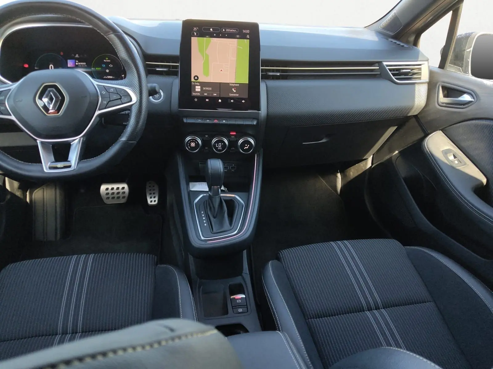 Vue intérieure avant de la Renault Clio V E-Tech, tableau de bord noir avec écran tactile central et volant multifonction.