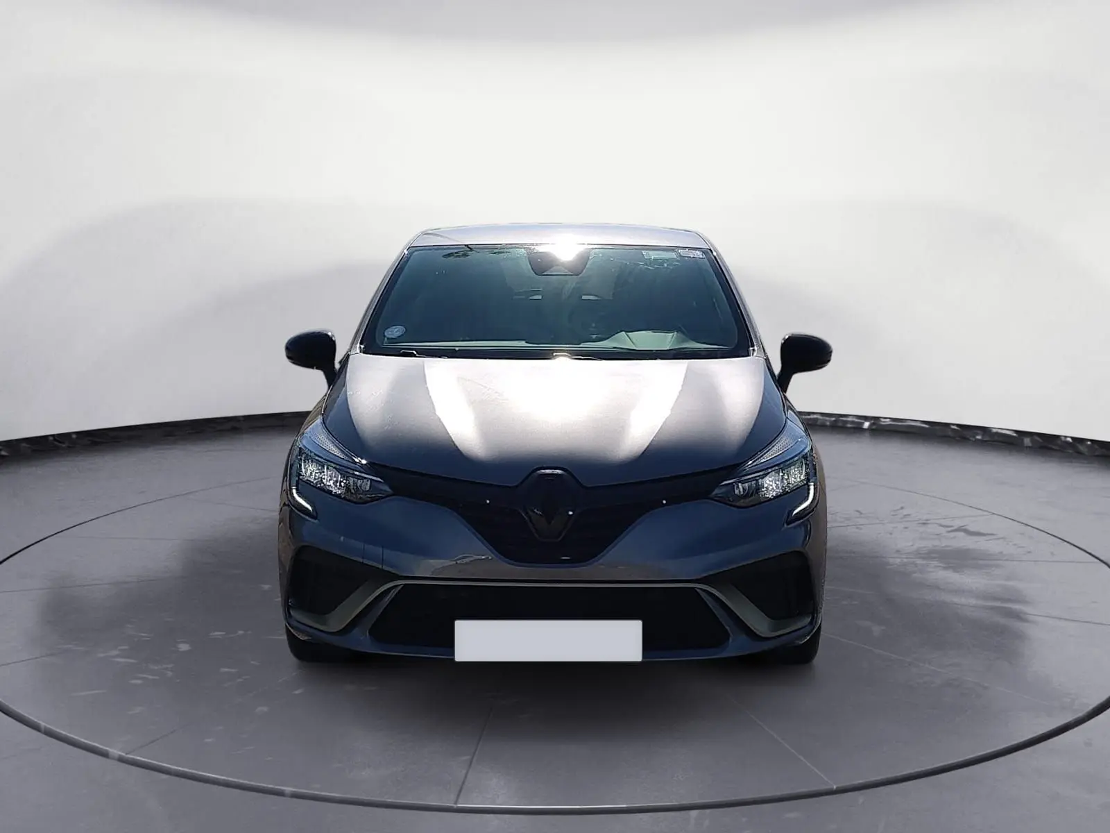 Vue de face d'une Renault Clio V E-Tech Full Hybrid 145 gris foncé métal, mettant en valeur ses phares LED et calandre noire.