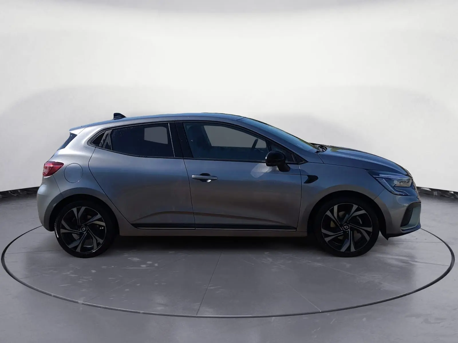 Profil droit d'une Renault Clio V E-Tech Full Hybrid 145 gris foncé métal avec jantes alliage noires et détails sportifs.