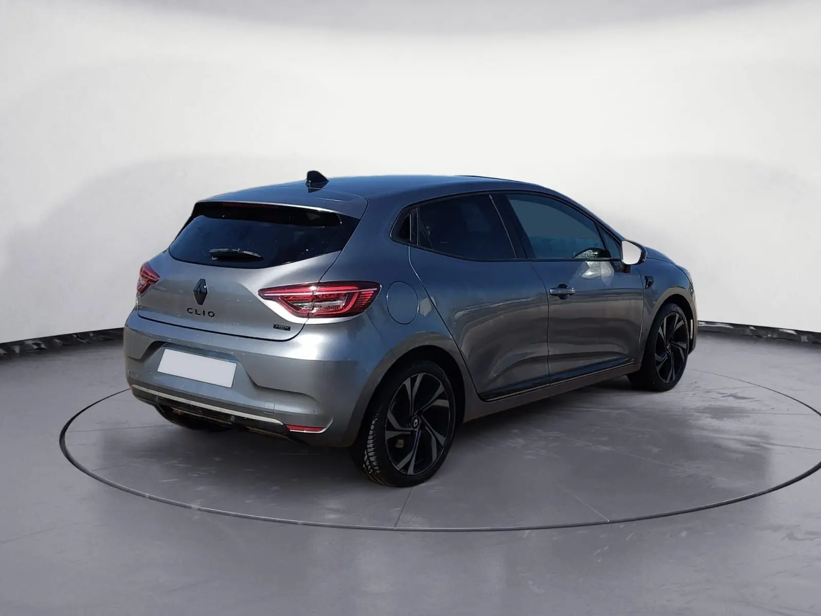 Renault Clio V E-Tech hybride gris foncé métal vue 3/4 arrière droit avec jantes noires et vitres teintées.