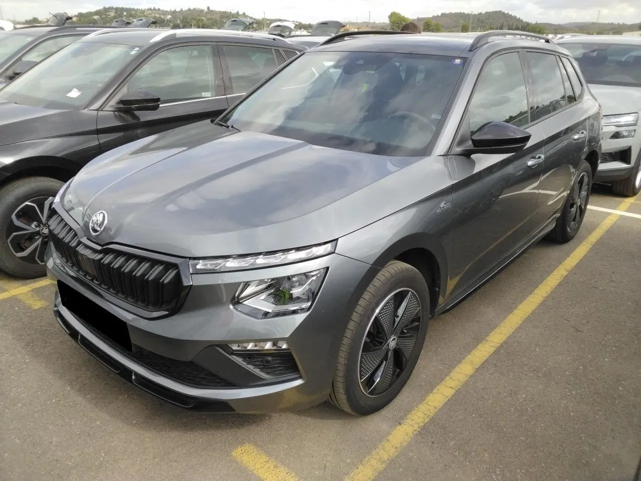 Vue 3/4 avant droite d'un Skoda Kamiq TSI 116 DSG7 Monte-Carlo gris graphite avec jantes noires et toit panoramique.