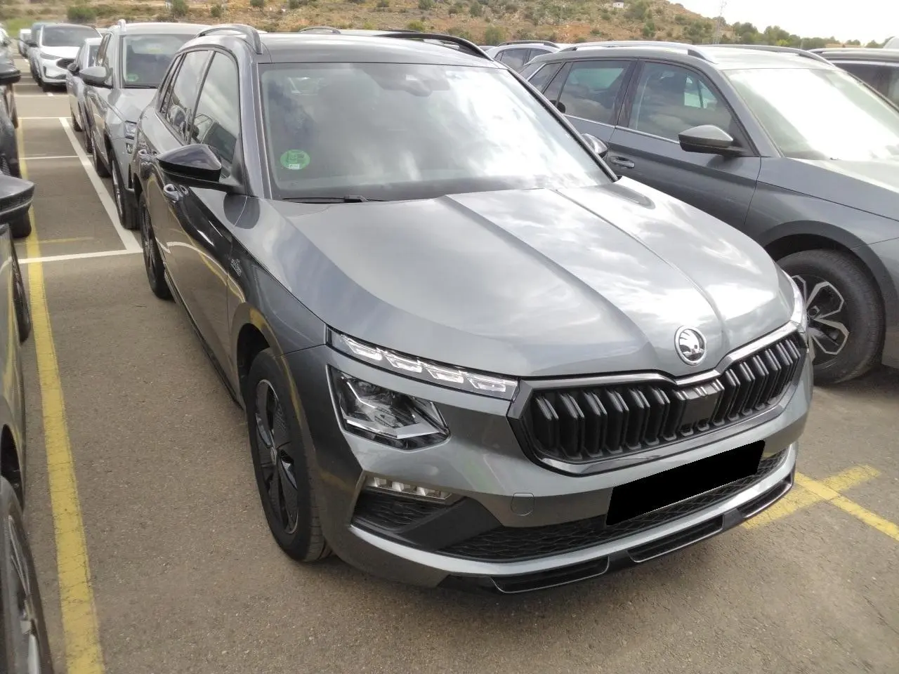 SKODA KAMIQ TSI 116 DSG7 Monte-Carlo gris graphite vu en 3/4 avant avec calandre noire et jantes spécifiques.