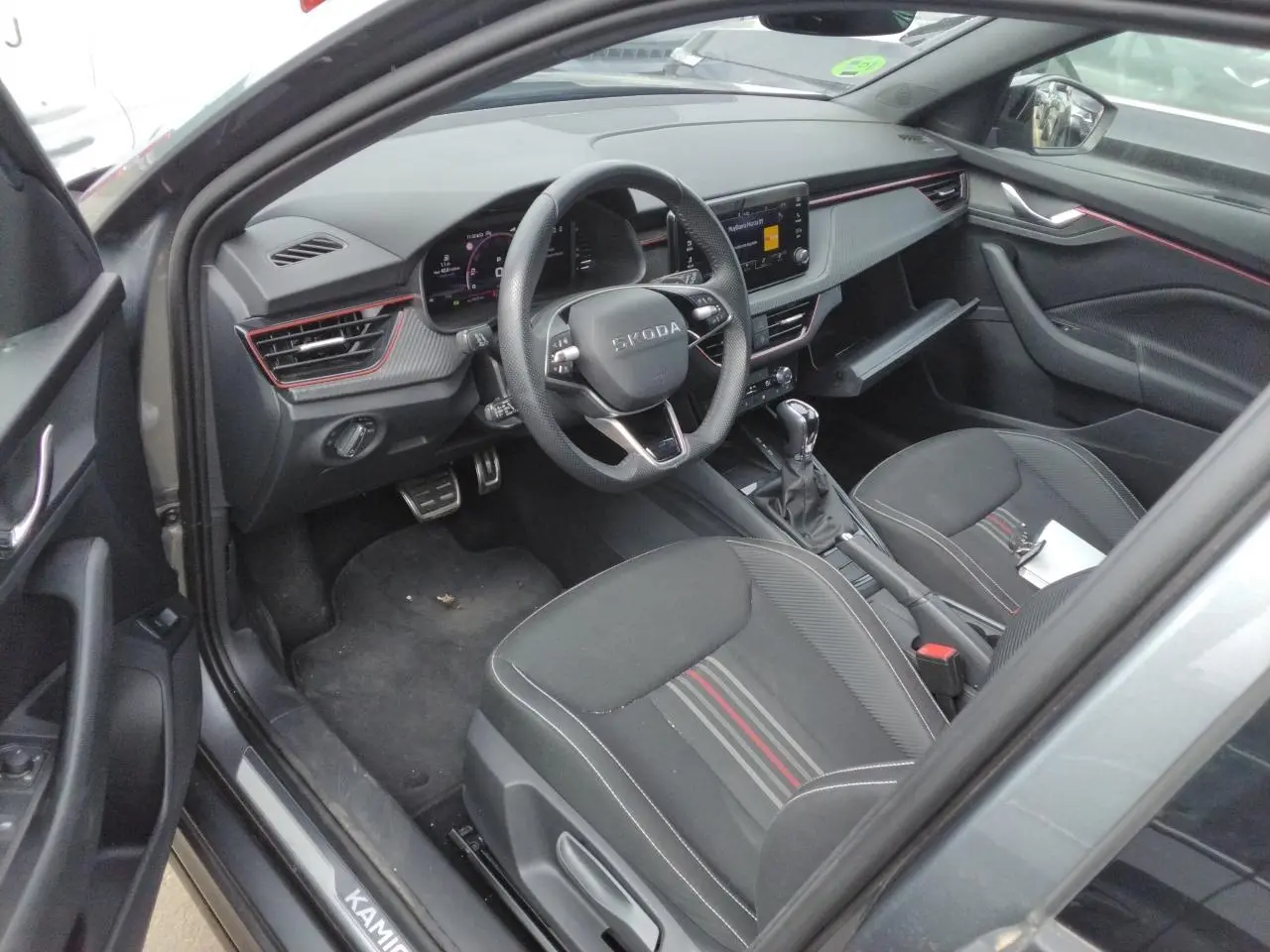 Vue intérieure côté conducteur du Skoda Kamiq gris graphite 2025, avec tableau de bord Monte-Carlo et volant cuir sport.
