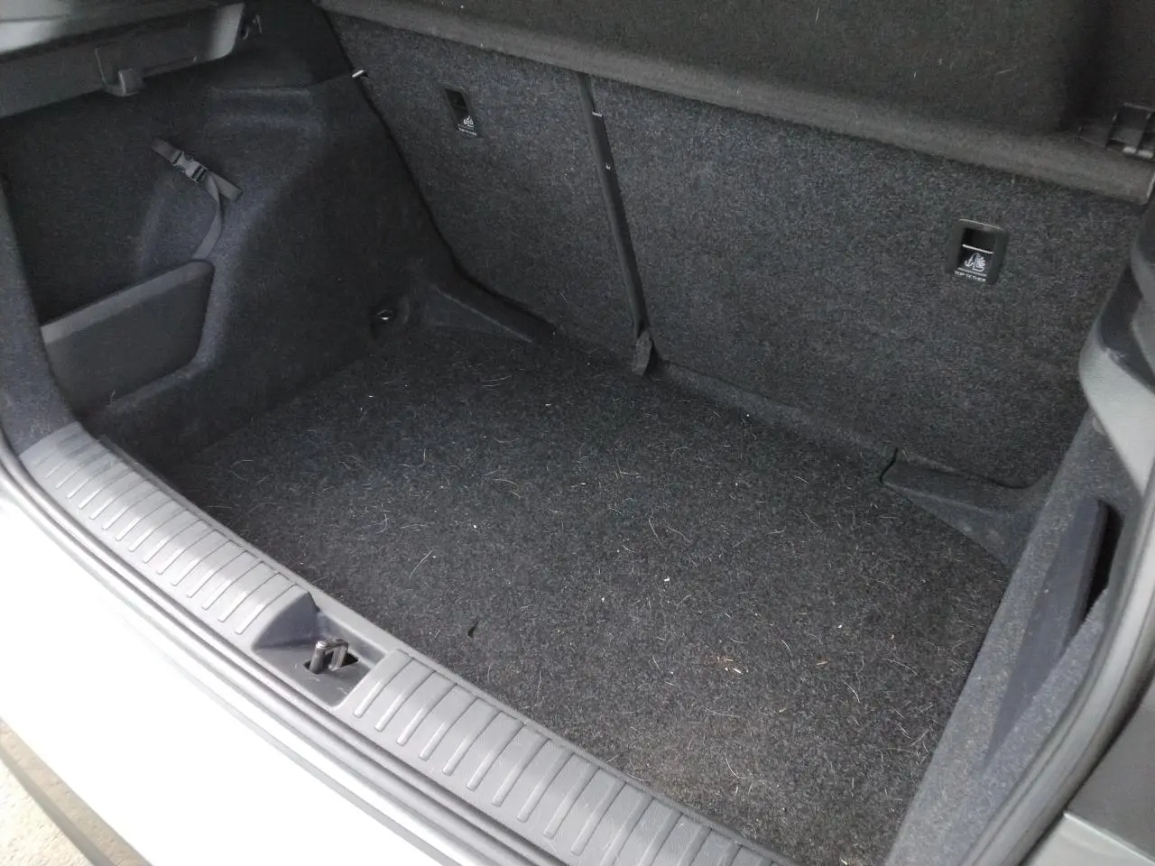 Vue intérieure du coffre ouvert du Skoda Kamiq TSI 116 DSG7 Monte-Carlo, moquette noire et garnitures sombres visibles.