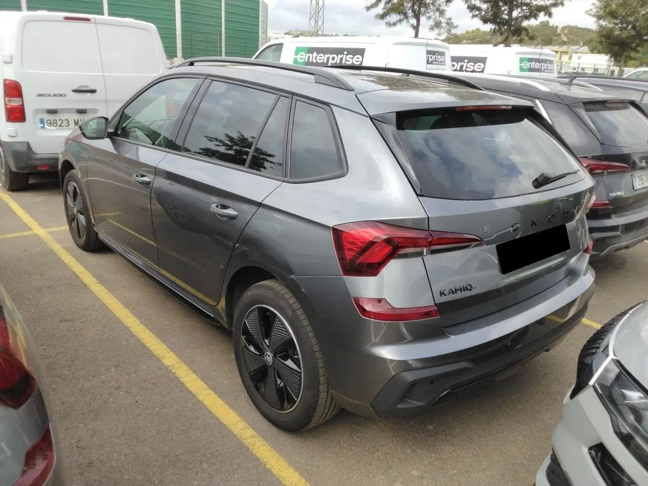 Vue 3/4 arrière droite d'un Skoda Kamiq gris graphite avec jantes alliage noires et toit panoramique.