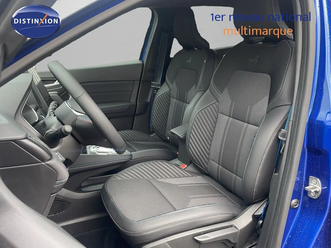Vue intérieure côté conducteur du Renault Captur E-Tech hybride 2025, sièges noirs avec surpiqûres bleues et logo Alpine brodé.