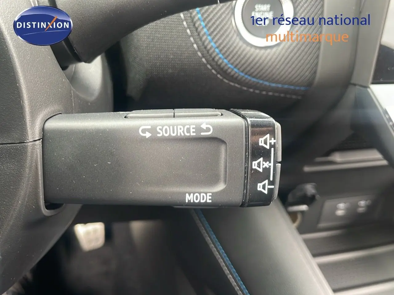 Gros plan sur la commande au volant du Renault Captur E-Tech hybride 2025, avec coutures bleues apparentes.