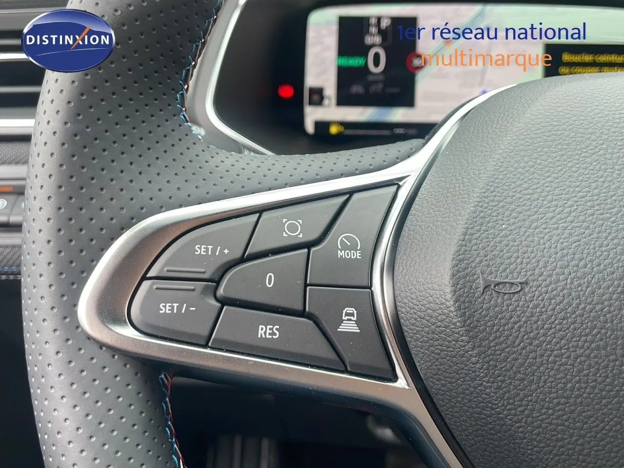 Gros plan sur les commandes au volant en cuir perforé du Renault Captur E-Tech hybride 2025, affichage numérique en arrière-plan.