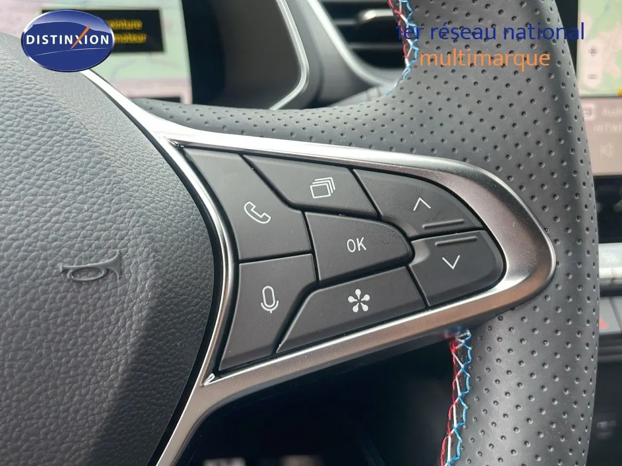 Gros plan sur les commandes multifonctions du volant en cuir perforé noir du Renault Captur E-Tech hybride 2025.