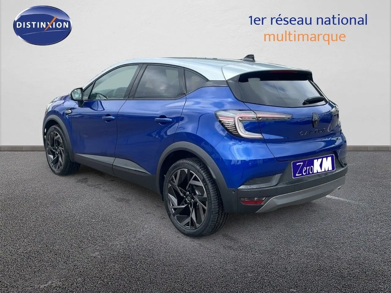 Renault Captur E-Tech hybride bleu Iron Metal avec toit gris, vue 3/4 arrière côté gauche, jantes noires distinctives.